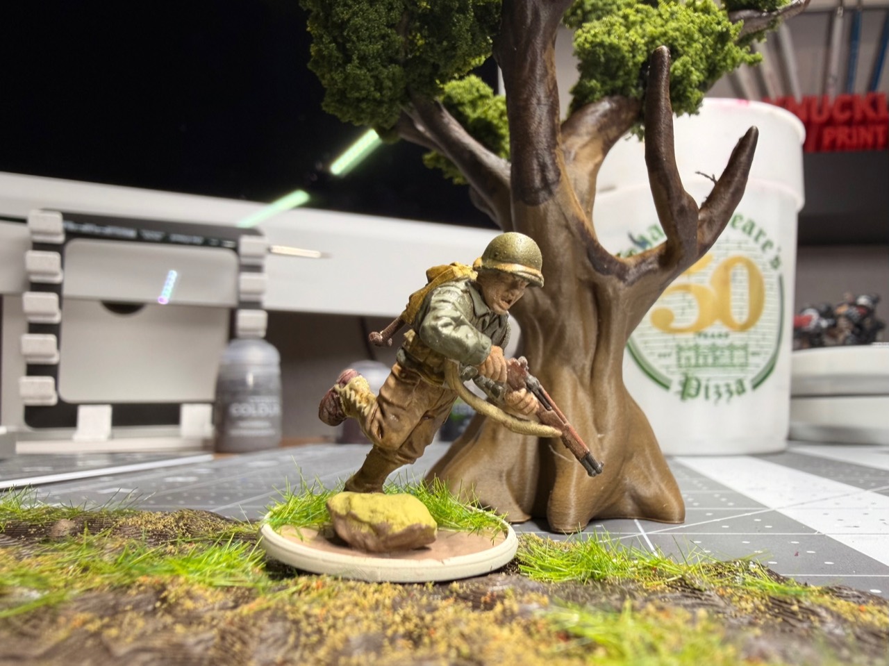 Painted World War II miniature beside terrain on the Knucklehead Miniatures workbench